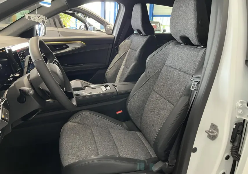 Intérieur avant droit de la Renault Rafale blanche 2025, sièges sport gris textile avec surpiqûres argentées.