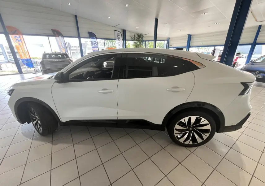 Profil côté gauche du Renault Rafale blanc 2025 en hybride, avec jantes alliage noires et détails noirs contrastants.