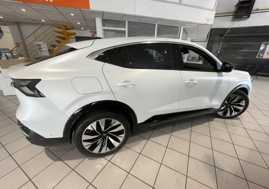 Vue latérale droite d'un Renault Rafale blanc 2025 avec jantes alliage noires et détails noirs contrastants.