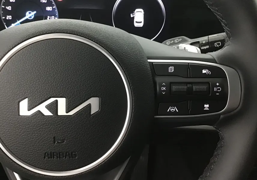 Vue rapprochée du volant cuir noir du KIA SPORTAGE 2025 avec commandes intégrées et logo KIA central gris Sirius.