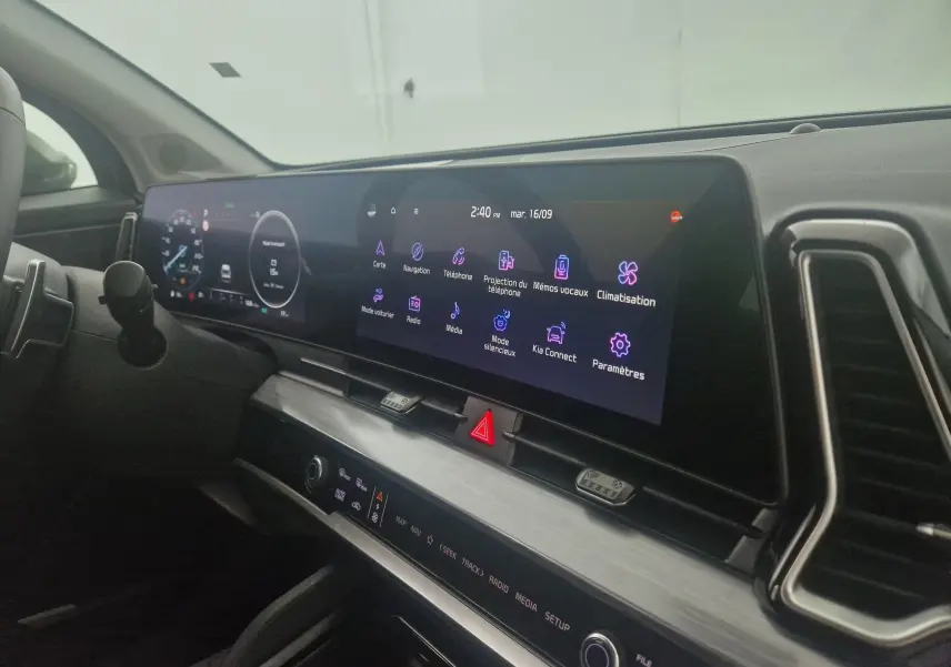 Vue intérieure du tableau de bord du KIA Sportage 2025, écran digital 12,3 pouces et commandes tactiles modernes.