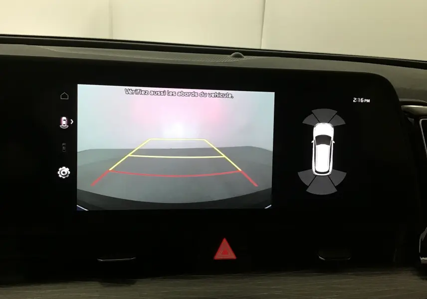 Écran digital 12,3 pouces du Kia Sportage 2025 affichant la caméra de recul et l'alerte de proximité du véhicule.
