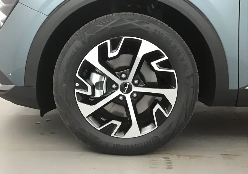 Gros plan sur la roue avant gauche du KIA SPORTAGE gris Sirius, mettant en valeur la jante alliage 18 pouces au design moderne.