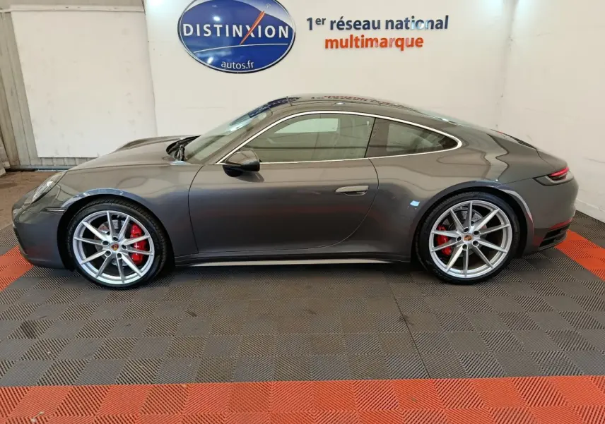Vue de profil côté gauche d'une Porsche 911 Carrera 4S Coupé gris foncé avec freins rouges et jantes argentées.