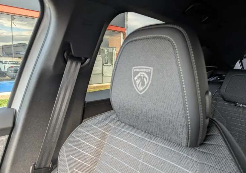 Détail du siège avant gris avec logo Peugeot embossé, vue intérieure côté gauche du Peugeot 3008 blanc 2025.