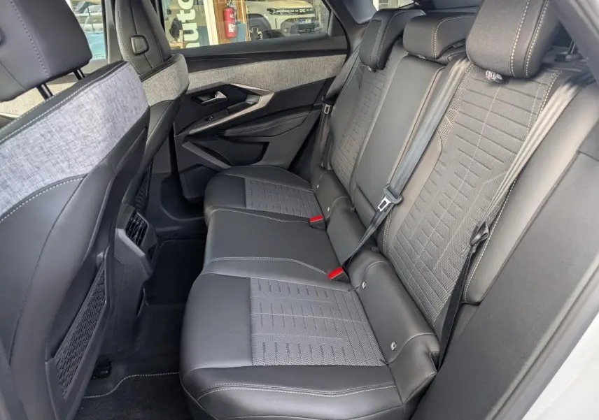 Vue côté droit de la banquette arrière en tissu gris et cuir noir du Peugeot 3008 blanc, avec ceinture de sécurité et appuie-têtes.