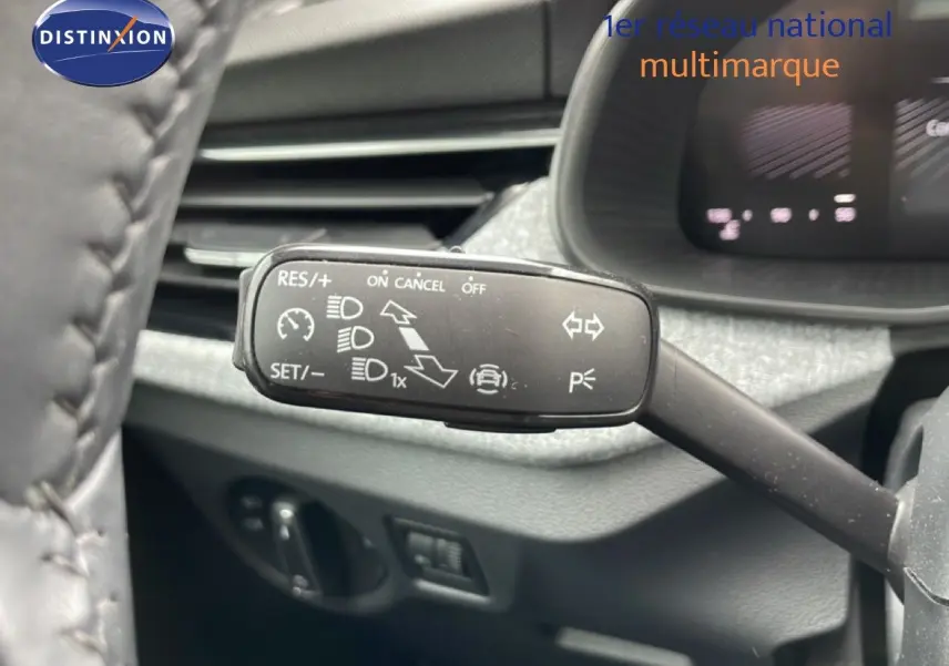 Gros plan sur la commande de régulateur de vitesse à gauche du volant dans l’habitacle gris noir d’une Skoda Scala noir magique métal.