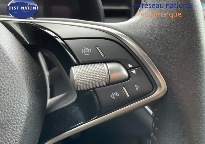 Gros plan sur les commandes au volant d'une Skoda Scala 2025, finition noire avec détails chromés et molette texturée.