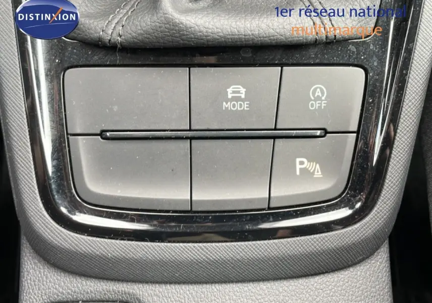 Vue rapprochée du tableau de commandes centrales de la Skoda Scala noire, mettant en valeur les boutons de mode et assistance au stationnement.