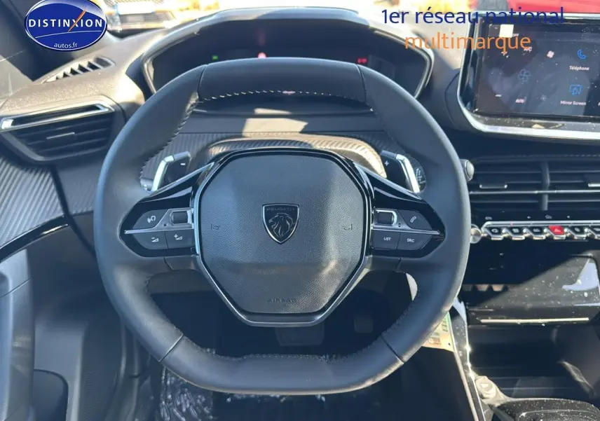 Vue rapprochée du volant noir de la Peugeot 2008 1.2 hybrid 145 allure avec commandes multifonctions et tableau de bord moderne.