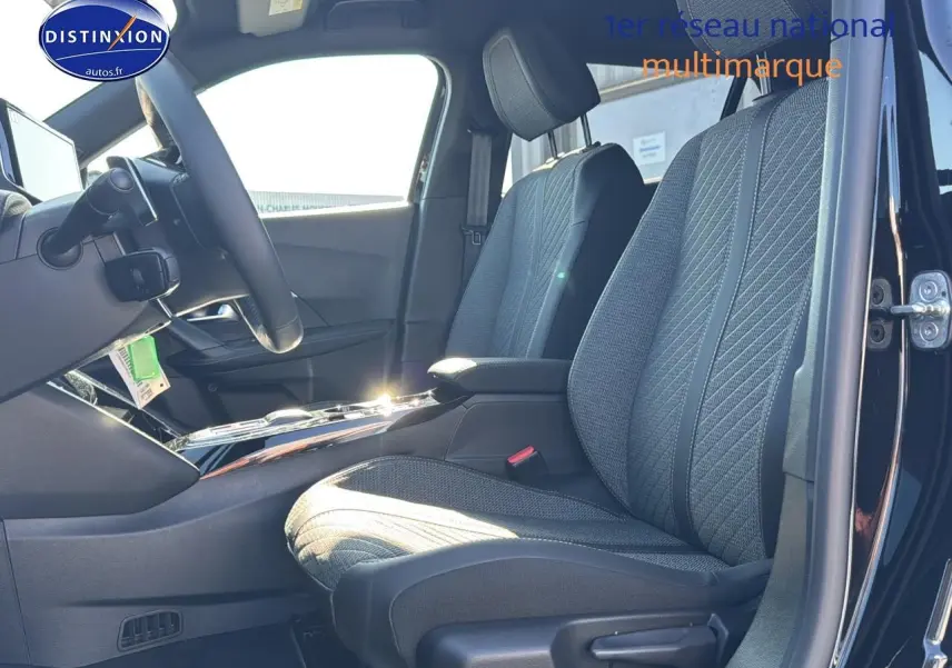 Intérieur de la Peugeot 2008 noir, vue côté conducteur montrant les sièges tissu gris et le volant multifonction.