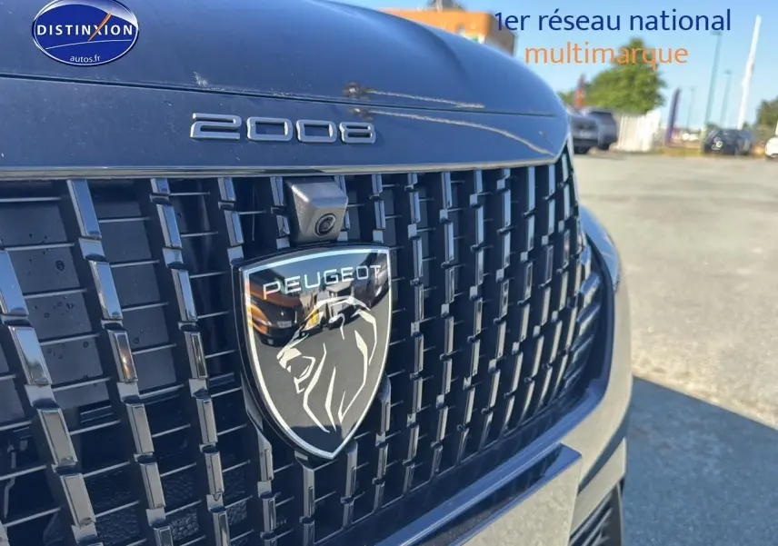 Gros plan sur la calandre noire du Peugeot 2008 2025 avec logo lion et caméra frontale intégrée.