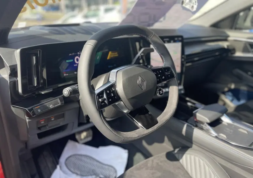 Intérieur Renault Rafale 2025 vu côté conducteur, volant Alcantara avec surpiqûres tricolores et écran tactile vertical.