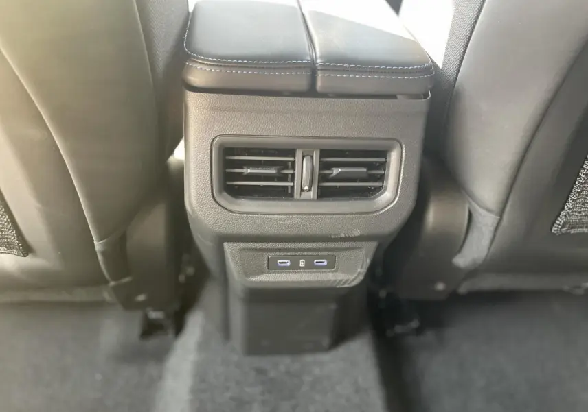 Prise USB-C et bouche d'aération arrière sur la console centrale noire entre les sièges arrière d'une Renault Rafale rouge toit noir.