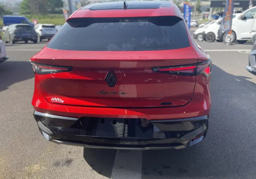 Vue arrière d'une Renault Rafale rouge à toit noir, avec feux arrière LED et logo central noir sur parking.