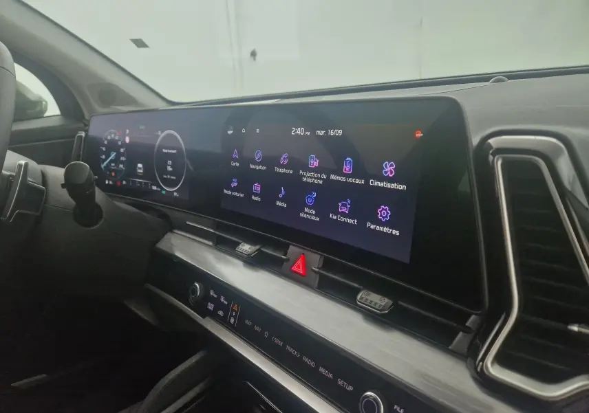 Vue rapprochée du tableau de bord digital 12,3'' du Kia Sportage blanc 2025 avec écran tactile et commandes intégrées.
