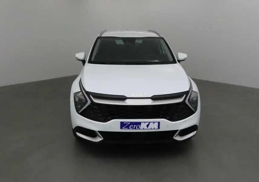 Vue frontale d'un Kia Sportage blanc 2025 avec calandre noire et logo Kia moderne sur capot.