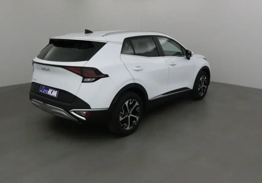 KIA Sportage blanc vu en 3/4 arrière droit, avec jantes noires et feux arrière LED profilés.