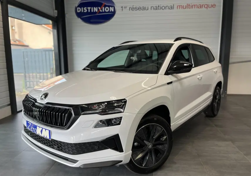 Vue 3/4 avant droite d’un SUV Skoda Karoq blanc 2025 avec calandre noire et jantes alliage noires Sportline.