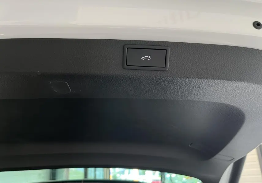 Bouton d'ouverture électrique du hayon sur la face intérieure du coffre d'un Skoda Karoq blanc.