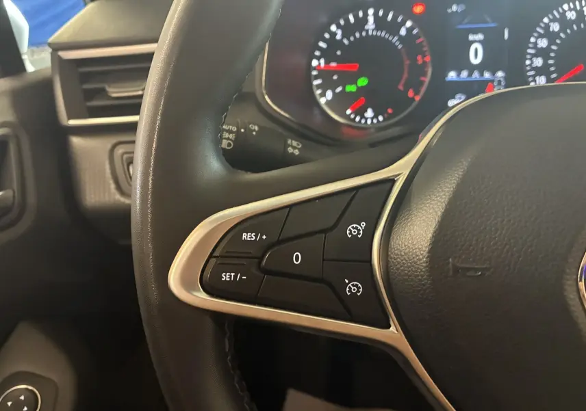 Gros plan sur le volant noir de la Renault Clio 1.5 BlueDCI Business 2022, avec commandes de régulateur de vitesse visibles.