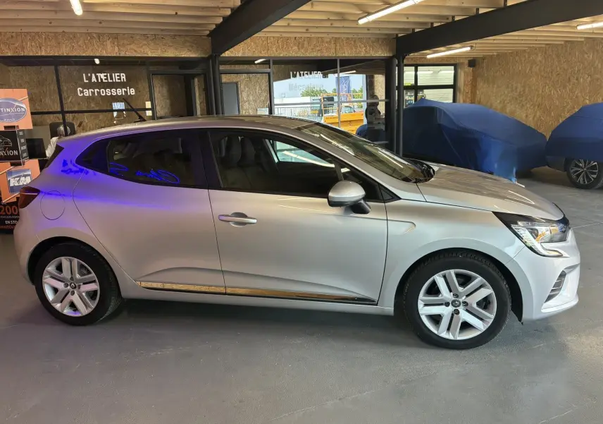 Profil côté gauche d'une Renault Clio 1.5 BlueDCI Business gris 2022, avec jantes alliage et vitres teintées.