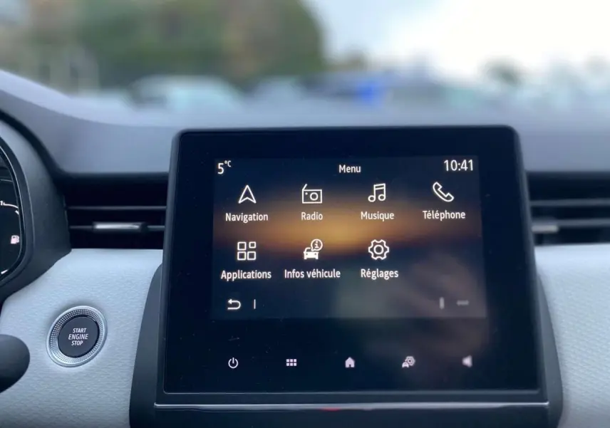 Écran tactile multimédia 7 pouces affichant le menu principal dans l'habitacle clair d'une Renault Clio blanche.