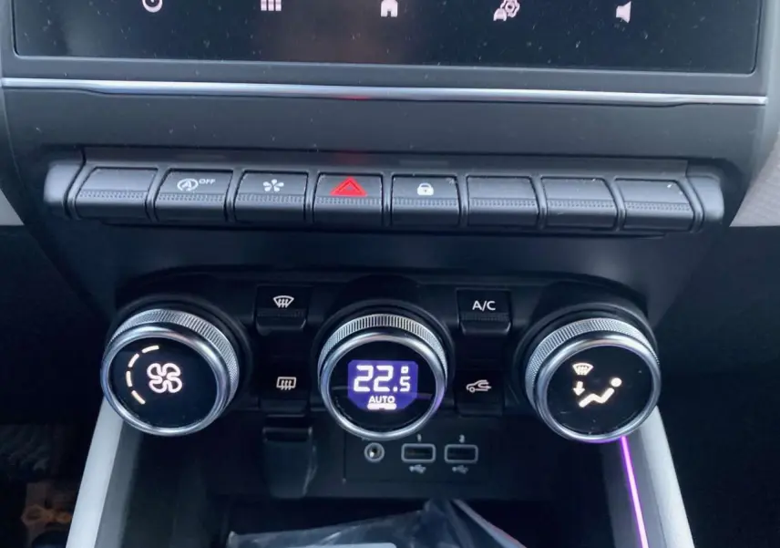 Gros plan sur la console centrale de la Renault Clio blanche 2023, montrant les commandes de climatisation automatique et ports USB.