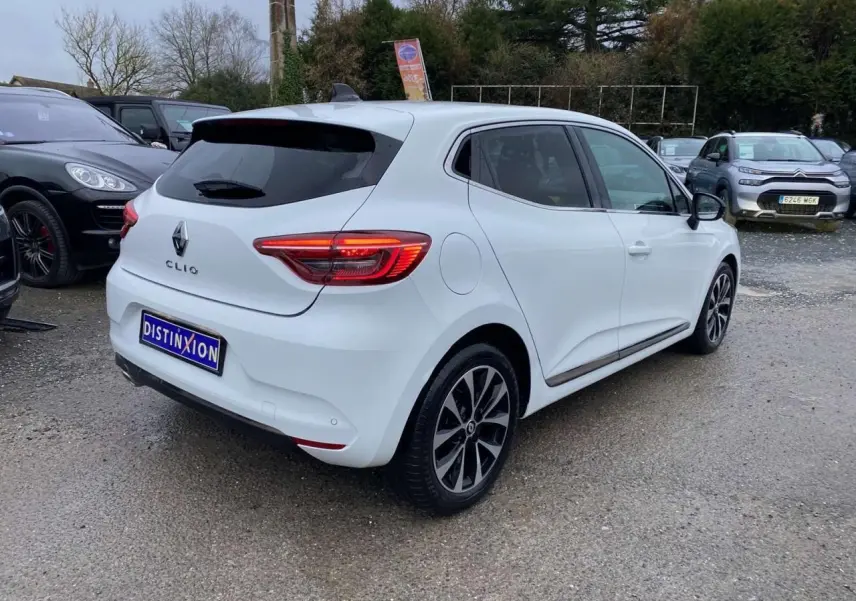 Renault Clio blanc Glacier vue 3/4 arrière droit, avec jantes alliage noires et vitres surteintées.