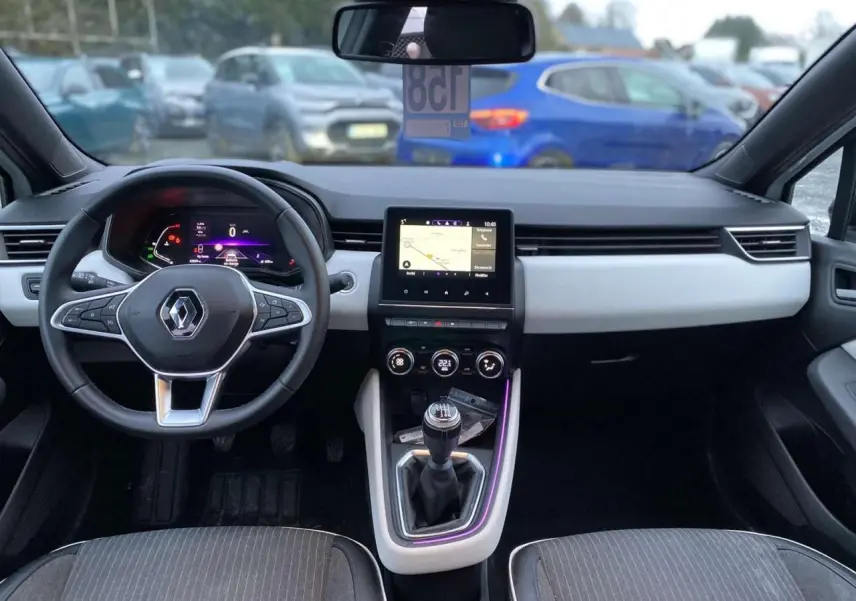 Intérieur de Renault Clio 2023 vu de face, tableau de bord moderne avec écran tactile et levier de vitesse manuel.