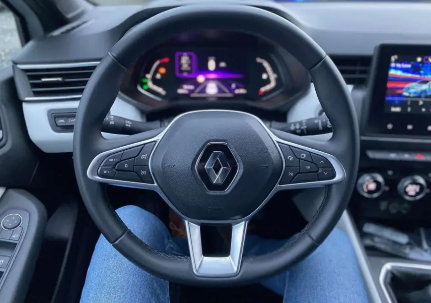 Vue centrée sur le volant noir de la Renault Clio 2023 avec tableau de bord numérique et écran tactile visible.