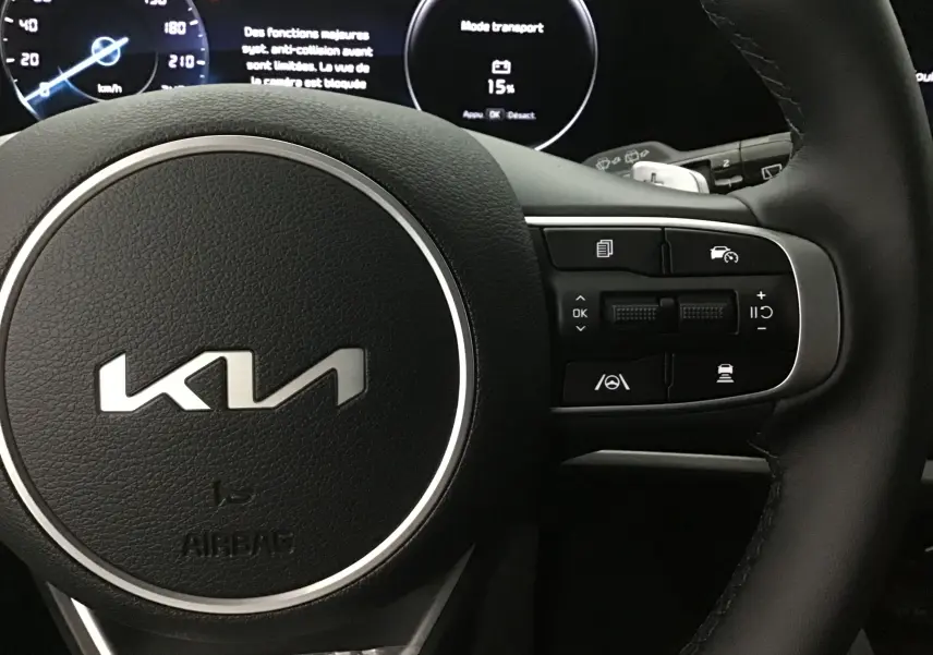 Gros plan sur le volant cuir du Kia Sportage 2025 avec commandes intégrées et combiné d'instrumentation digital.