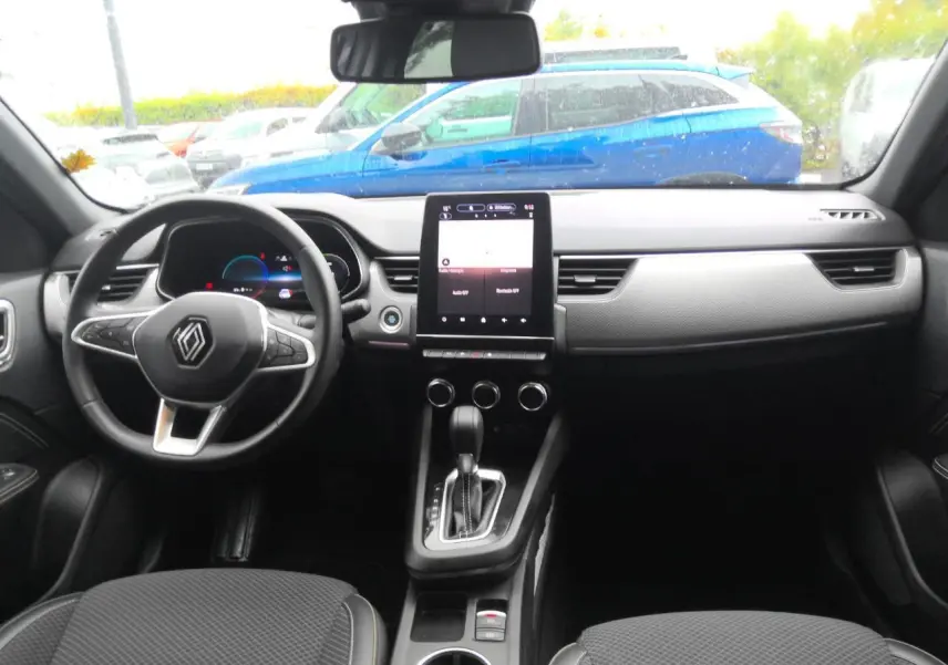 Intérieur du Renault Arkana 2024, vue avant du tableau de bord avec écran tactile vertical et volant en textile noir.