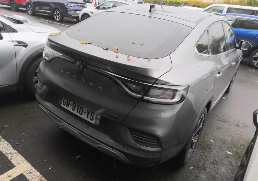 Vue 3/4 arrière droit du Renault Arkana gris métal foncé avec toit ouvrant et feux arrière LED reliés par un bandeau noir.