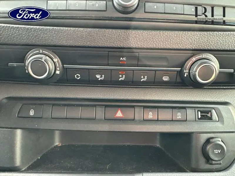 Tableau de bord noir du Peugeot Expert Fourgon 2022, avec commandes climatisation et prise 12V visibles en gros plan