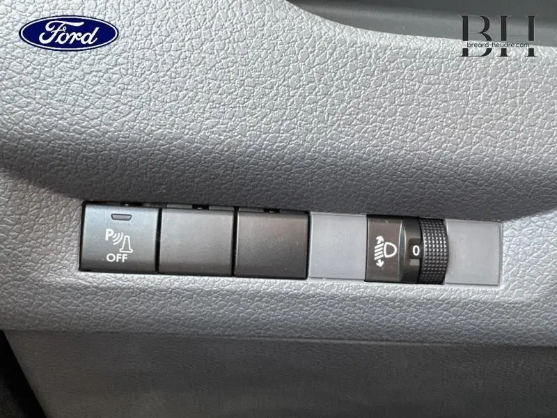 Panneau de commandes intérieur gris avec bouton désactivation aide au stationnement et réglage hauteur phares sur Peugeot Expert Fourgon noir.
