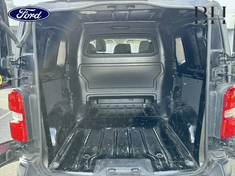 Vue arrière du fourgon PEUGEOT Expert noir Perla Nera montrant l'espace de chargement vide avec cloison fixe et plancher métal.