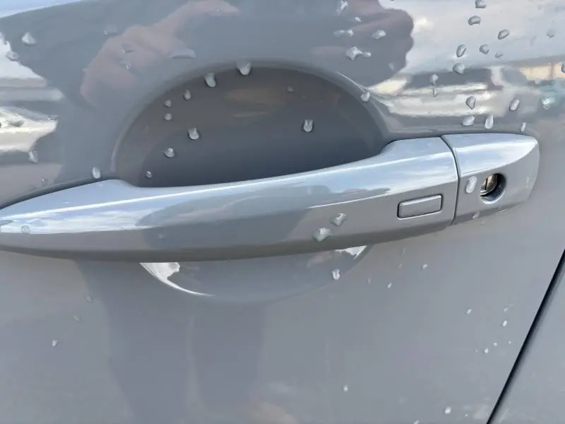 Poignée de porte gris argile du Nissan Qashqai e-POWER 2024 avec bouton d'ouverture et détecteur de présence.