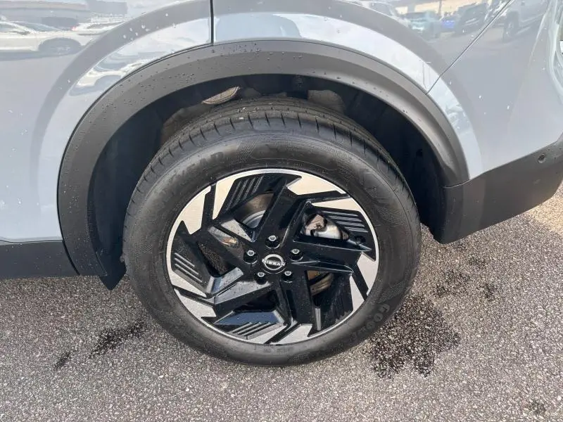 Gros plan sur la roue avant droite du Nissan Qashqai e-POWER gris Argile, avec jante alliage noire et argentée au design moderne.
