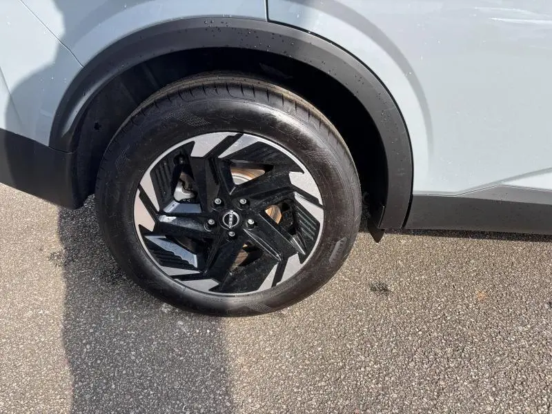 Gros plan sur la roue avant gauche avec jante noire et argent du Nissan Qashqai e-POWER gris Argile 2024