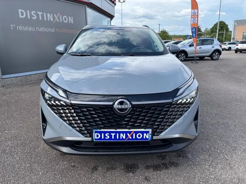 Vue frontale d'un Nissan Qashqai e-POWER gris Argile avec calandre noire texturée et logo Nissan centré.