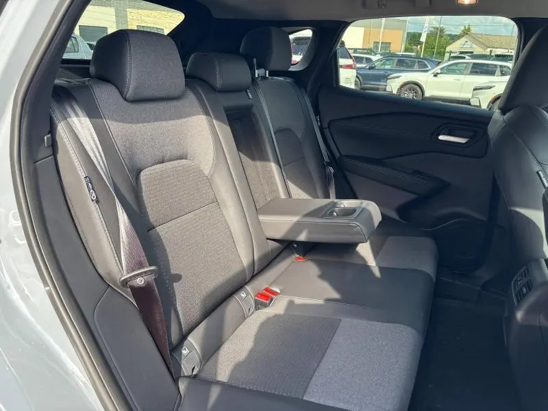 Vue intérieure côté gauche des sièges arrière gris mixte tissu et TEP du Nissan Qashqai e-POWER 2024 avec accoudoir central abaissé.