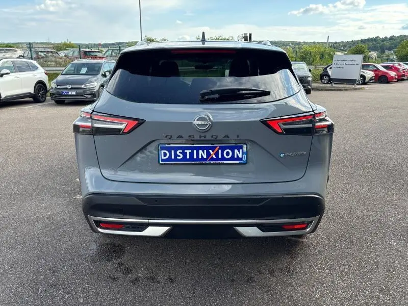 Vue arrière d'un Nissan Qashqai e-POWER gris Argile avec feux LED et logo distinctif sur parking extérieur.