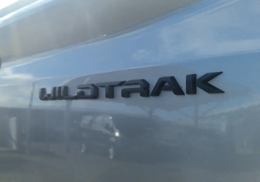Gros plan sur l’inscription Wildtrak en relief noir sur la carrosserie gris iconic d’un Ford Ranger Super Cabine 2025.