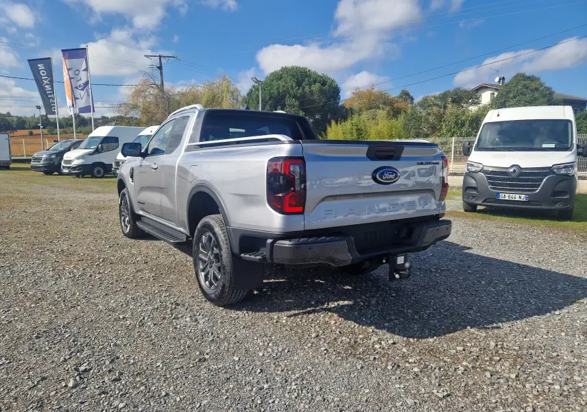 Ford Ranger Super Cabine gris iconic vu en 3/4 arrière droit, avec benne protégée et attelage visible.