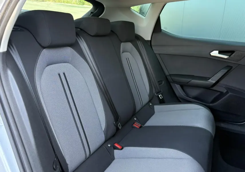Vue latérale droite des sièges arrière gris clair et noir de la SEAT LEON 2.0 TDI 2024 avec vitres surteintées.