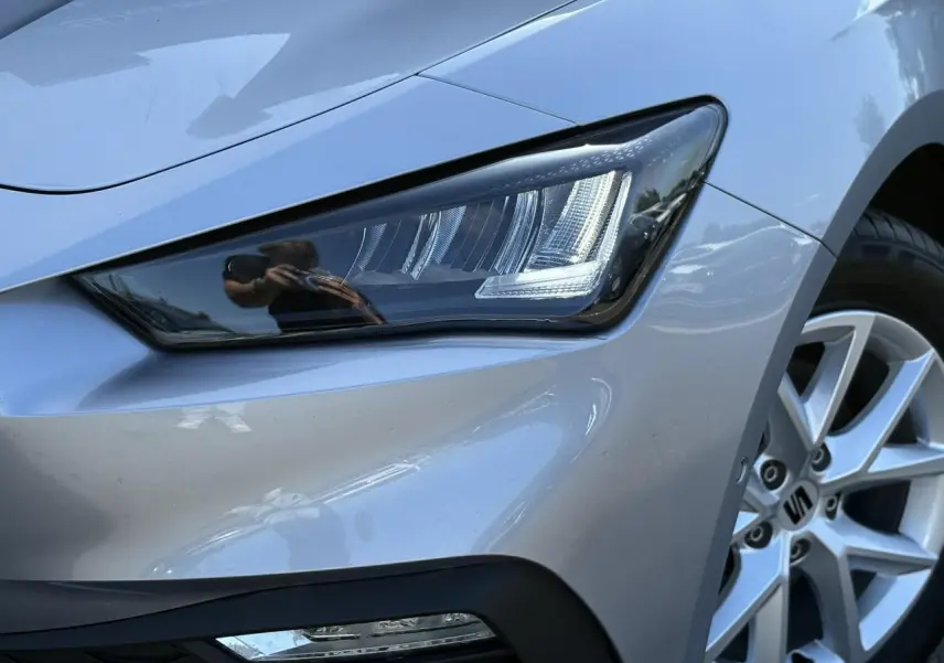 Gros plan sur le phare avant droit et la jante alliage gris argent d'une SEAT LEON 2.0 TDI 2024.