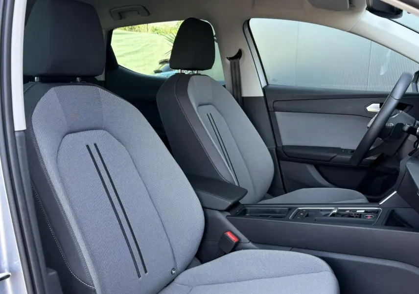 Intérieur avant de la SEAT LEON 2.0 TDI gris argent, vue côté droit sur sièges tissu gris et console centrale noire.