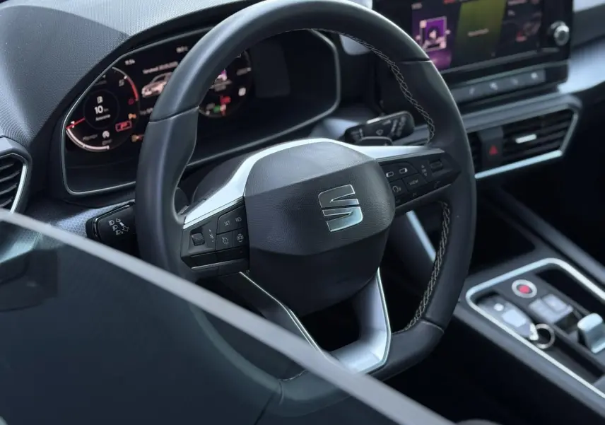 Vue rapprochée du volant cuir multifonction et du tableau de bord numérique du SEAT LEON gris argent 2024.