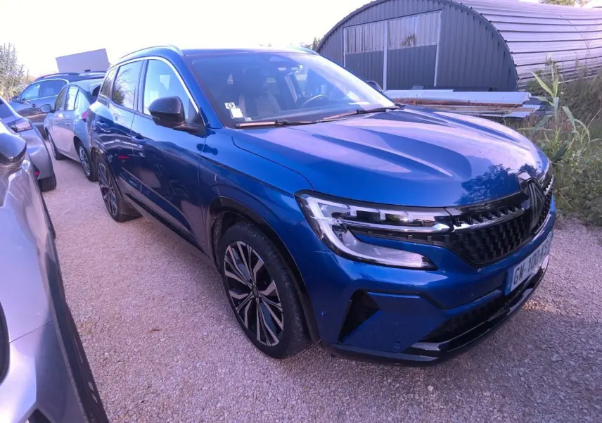 Renault Austral bleu métal foncé vu en 3/4 avant droit avec calandre damier et jantes alliage 20 pouces.